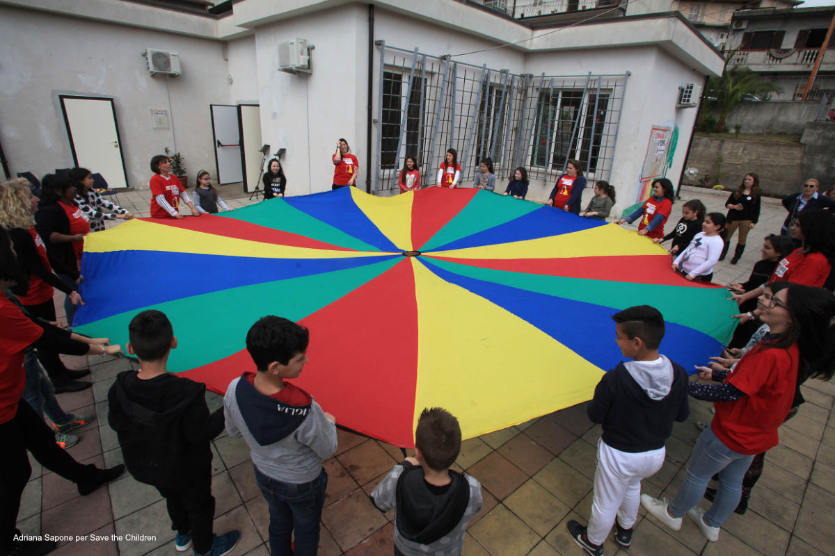 Gruppo di bambini in cerchio che tiene un grande cerchio di tessuto multicolor